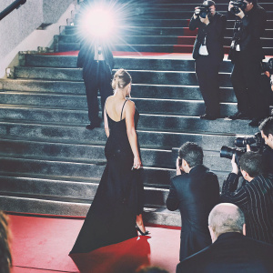 Cassie Scerbo at Cannes Film Festival premiere. Wearing elegant black dress. Red carpet, flashing cameras