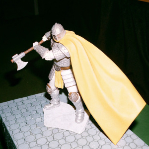 Fantasy warrior figure in a battle stance, wielding a battle axe and adorned with a flowing cape. The detailed 3D render showcases intricate textures and dramatic lighting. Set against a dark background, the warrior stands on a textured stone platform.