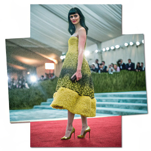 Krysten Ritter at the Met Gala, wearing a vibrant yellow and black gown with intricate textures and gold heels. She stands confidently on a red carpet with a glamorous backdrop.