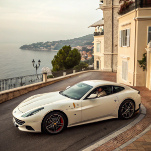 White Ferrari GTC4 Lusso parked on the streets of Monaco. Richly detailed exterior. Expansive sea view in the background.