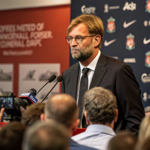 Jurgen Klopp, Liverpool FC manager, wearing a dark suit and tie. Speaking at a press conference with reporters.