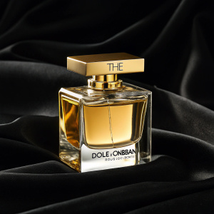 Luxury perfume bottle of 'The One' by Dolce & Gabbana. Elegant black background, highlighting the golden cap and clear liquid inside.