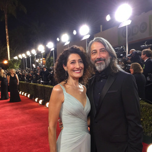 Lisa Edelstein and Robert Russell at a glamorous gala event. Bright lights and red carpet in the background.