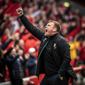 David Flitcroft, the energetic Barnsley manager, mid-shout at a packed stadium. Background a blur of passionate fans