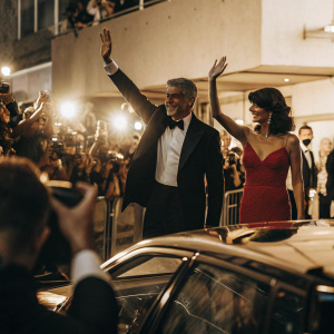 George Clooney and Celine Balidran at Cannes Film Festival premiere. Glamorous evening attire, waving to fans on crowded red carpet.