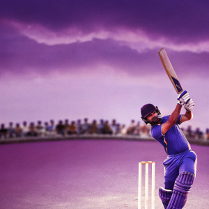 High-resolution action shot of Virat Kohli in vibrant blue uniform. Cricket bat raised, in a powerful stance. Crowd blurred in background