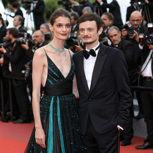 Karen Rebecca Casiraghi and Fabio Rovazzi at Cannes Film Festival. She is in a stunning black gown with teal highlights, he in a tuxedo. Surrounded by flashing cameras and paparazzi.