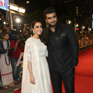 Shraddha Kapoor and Arjun Kapoor at premiere event, Shraddha in white traditional attire, Arjun in black suit. Crowded red carpet scene.