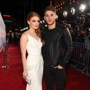Holland Roden and Cody Christian on a glamorous red carpet event. Holland wearing an elegant white gown, Cody in stylish black attire.