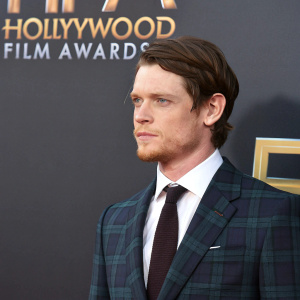 Jack O'Connell, Caucasian, medium build, at Hollywood Film Awards. Wearing a dark plaid suit, dark tie, crisp white shirt. Dark backdrop, Hollywood Film Awards logos.
