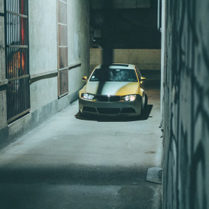 Customized BMW M4 parked in an urban alleyway. Graffiti-styled walls, dimly lit, evening atmosphere.