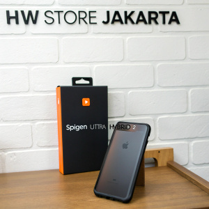 A sleek, black iPhone 7 Plus Spigen Ultra Hybrid 2 case placed next to its orange logo packaged box. Shot against a simple wooden desk with white wall backdrop. Overlaid with 'HW STORE JAKARTA' text