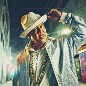 Daddy Yankee posing in urban setting, wearing his signature hat and chains. Promoting his Cangri lifestyle brand.