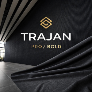 A sleek digital graphic featuring 'TRAJAN PRO/BOLD' in a bold sans-serif font atop a dark, textured background. Below the main text, a uniquely designed, smaller logo adds a modern touch. The overall aesthetic is contemporary and sophisticated, emphasizing the brand name with a minimalist approach.