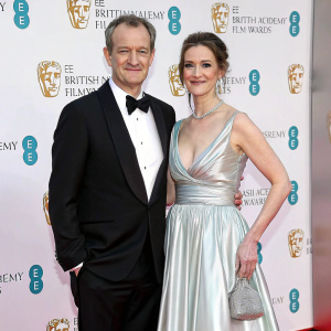 Alexander Armstrong and Hannah Bronwen Snow at the BAFTA Film Awards. They are both elegantly dressed. Armstrong in black tuxedo, Snow in floor-length silver gown.