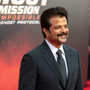 Anil Kapoor, Indian actor, at Hollywood premiere of Mission: Impossible - Ghost Protocol. Wearing dark suit and tie, smiling. Backdrop has bold, vibrant colors with film logo.