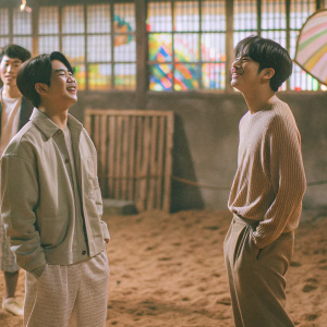 GOT7 members, standing in a casual setting. Lively atmosphere, colorful backdrop