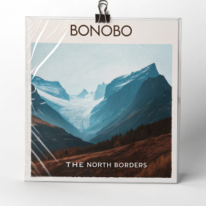 Album cover for Bonobo's 'The North Borders'. Symmetrical digital art with metallic clip and clear plastic wrap. Blue and brown colors. Set against a stark white background.