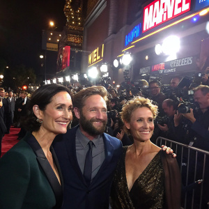 Carrie-Anne Moss, Joseph Coleman, and Janet McTeer at the premiere of a new Marvel film. Crowded venue, bright lights, and numerous cameras