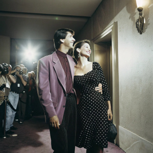 Alan Ruck and Claudia Ruck at the Hollywood premiere of Young Guns 2. Crowd of photographers and onlookers. Alan in purple blazer, Claudia in black polka dot dress. Indoor event, warmly lit