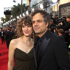 Mark Ruffalo and Bella Noche Ruffalo at the Golden Globe Awards. Mark in a dark suit, Bella with curly hair. Crowded red carpet with flashing cameras and award logos