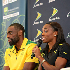 Tyson Gay and Veronica Campbell in a press conference. Sportswear brand logo behind them. Question and answer session