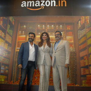 Raj Kundra, Shilpa Shetty Kundra, and Vikas Purohit at the launch event of a new Amazon.in product. The backdrop features the Amazon logo and vibrant product images.