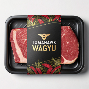 Premium packaging design for Tomahawk's Wagyu beef product. Showcases a sliced beef steak on a black tray. Red and gold accents. Brand name 'Tomahawk' and Thai text 'Wagyu' prominently displayed. Emphasizes high quality.