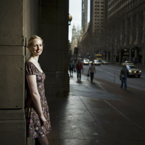 Deborah Ann Woll in a candid photo. Wearing a floral dress, standing in a bustling city street.