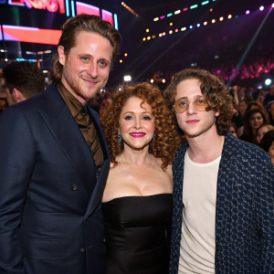Cameron Douglas, Bernadette Peters, and Rory Culkin posing together at an awards show. Crowded, colorful backdrop.