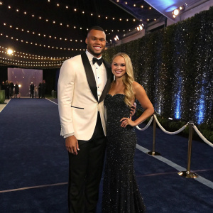Dak Prescott and Natalie Buffett at a glitzy awards ceremony. Dark blue carpet, sparkling lights in the background.