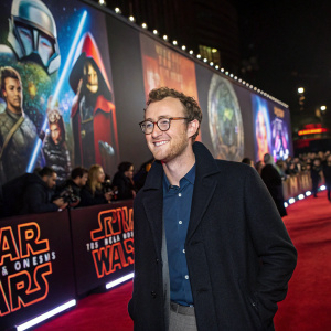 Francis Boulle, with a welcoming smile and glasses, at a star-studded premiere. The backdrop showcases vibrant star wars logos and characters.