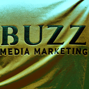 Close-up of the Buzz Media Marketing logo on a rough green fabric. Textured, modern font, metallic green sheen. Soft lighting, uneven surface.