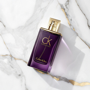 Calvin Klein perfume ad. Luxurious dark purple perfume bottle with gold cap. White marble background.