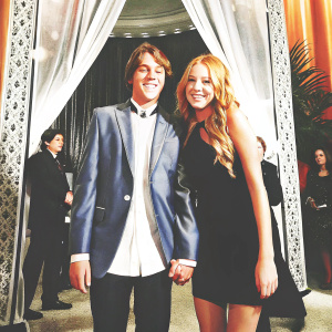 Michael Lohan Jr and Lindsay Lohan, siblings, posing for a photo at a glamorous gala event. Michael in a stylish blue blazer, Lindsay in a sleek black dress. Both smiling brightly.