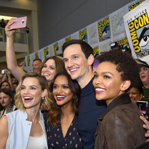 Robin Taylor, Erin Richards, Jessica Lucas, Cory Michael Smith, and Camren Bicondova at the Comic-Con convention, posing together with a group of excited fans in the background.