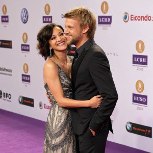 Miriam Pielhau and Thomas Hanreich on the purple carpet at the Echo Awards 2010. They are embracing with a backdrop of sponsor logos.