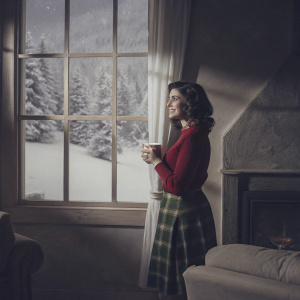 Audrey Horne, from Twin Peaks, in a cozy cabin. Wearing a red sweater and green plaid skirt. A serene, snowy landscape visible through the window