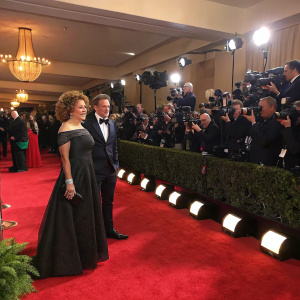 Alex Kingston and Florian Haertel at a vibrant awards show. Red carpet, paparazzi, and audience in formal attire.