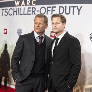 Til Schweiger and DJ Smash attend the 'Tschiller: Off Duty' film premiere. The backdrop features prominent logos of Warc, NDR, and other sponsors. Both men are dressed in formal attire with neutral expressions.