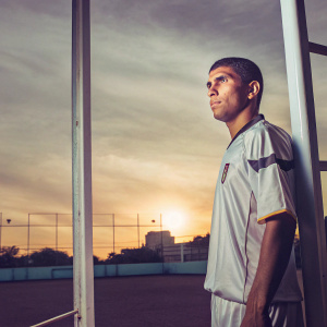 Arturo Vidal, intense focus, short hair, wearing jersey with crest. Silhouette against sunset, pitch empty.