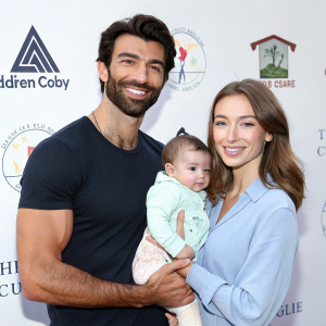 Justin Baldoni, Emily Foxler, and their baby Maiya Grace Baldoni at a charity gala. Justin has a beard and a muscular build. Emily has brown hair. Baby Maiya is in a light-colored onesie.