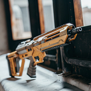 Concept art of a futuristic weapon from Shadowgun Legends. A high-tech rifle with a sleek, modern design, featuring vibrant yellow and brown hues, set against a black backdrop.