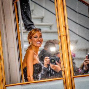 Petra Nemcova, at Cannes Film Festival, in black sequined gown. Flashing cameras, photographers in background. Candid moment with warm smile.