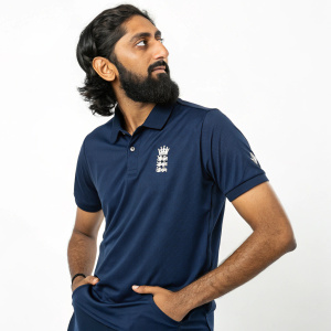 Cricket star Haseeb Hameed, bearded and wearing a navy blue polo shirt, at a high-profile sports award ceremony. Stark white background.