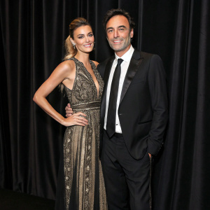 Anthony Delon and Sveva Alviti, dressed in formal attire, attending the premiere of a new film. Dark velvet curtain backdrop