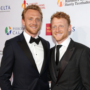 Kevin McKidd and Joseph McKidd at a gala event. Both are in formal wear, smiling. White background with sponsor logos