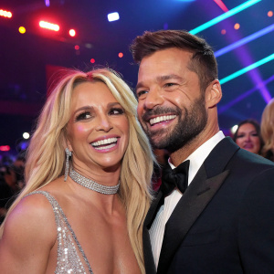 Britney Spears and Ricky Martin, flashing smiles at the GLAAD Media Awards. Neon lights and crowd in the background.