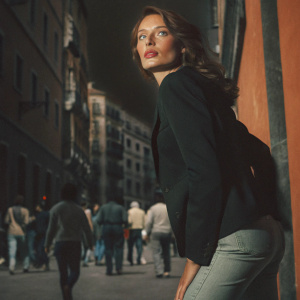 Saffron Burrows, looking intense. Wearing black blazer and skinny jeans. Standing in a crowded city street.