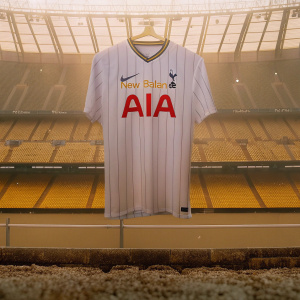 New Balance presents the Tottenham Hotspur 'AIA' edition jersey. Bright red 'AIA' wordmark on a sleek white shirt with pinstripes. Dark stadium backdrop